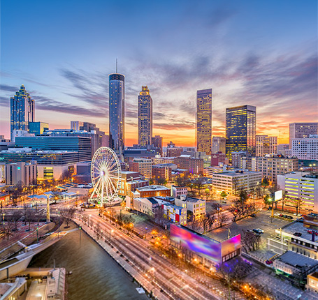 Downtown Atlanta skyline at sunset with high rise buildings, Ferris wheel and illuminated city streets